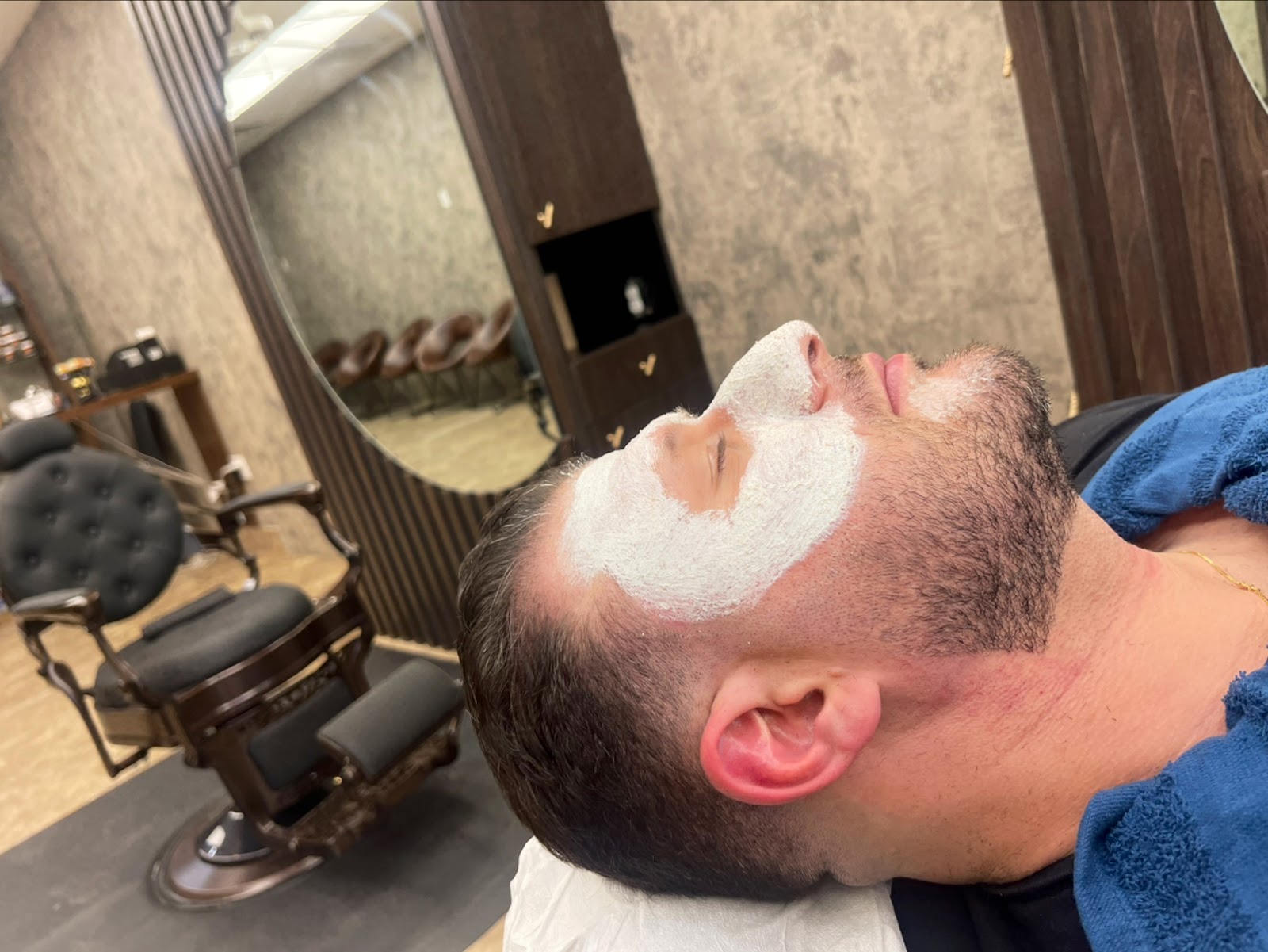 A facial in progress, mask on, reclined in the barber chair